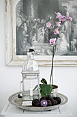 Deko-Stillleben mit Orchidee und Laterne auf rundem Silbertablett
