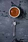 Homemade salted caramel sauce with grains of fleur de sel salt in ceramic bowl with spoon