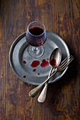 Red wine glass on a metal plate with cutlery