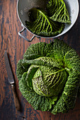 Whole cabbage, and savoy cabbage leaves in a vintage colander
