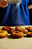 Spill powdered sugar on stack of fresh doughnuts while cooking pastry