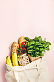 Flat-lay of healthy grocery shopping eco-friendly bag with fresh vegetables, fruit, bread, herbs and legumes