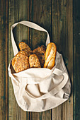 Eco bag with fresh bread on wooden background