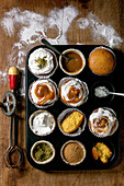 Homemade citrus oranges or clementines sweet muffins cupcakes in baked tray with vintage hand mixer, flour and different topping