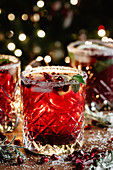 Pomegranate cocktail with mint and Christmas lights on the background