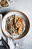 A healthy multigrain porridge with a topping of warm spiced pears and hazelnuts for a hearty breakfast.