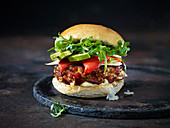 Ein spanischer Burger mit Chorizo und Salat vor dunklem Hintergrund