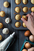 Garnishing mini muffins in a baking dish with whipped cream