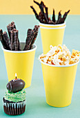 Cupcake mit Kerze sowie Biltong-Streifen und Popcorn für die Rugby-Party