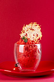 Fresh tomato sorbet glass decorated with cheese crisp over on red plate on red background