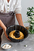 Unrecognizable female in apron showing off roll of soft dough into pan