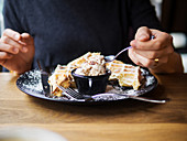 Frau isst Waffeln mit Puderzucker und Eiscreme