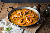 Paella with roasted shrimps on rustic table