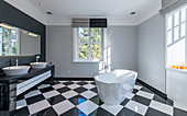 Free-standing bathtub and black-and-white chequered floor in modern bathroom