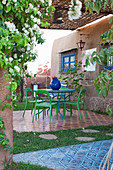 Modern garden furniture on terrace of patterned tiles outside house