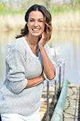 A young woman wearing a grey jumper near river