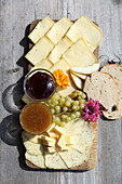 A cheese platter with alpine cheese, mustard dips, grapes and bread