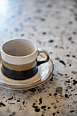 Three-coloured stoneware cup and saucer on terrazzo surface