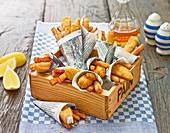 Fish and Chips as finger food, wrapped in newspaper, in a wood tray