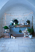 Christmas decorations on and around old cupboard below fairy lights