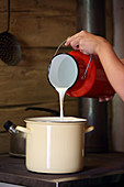 Milk being poured from a milk churn into a pot