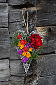 Wicker love-heart decorated with real geraniums and colourful paper flowers