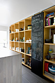 Chalkboard sliding door flanked by shelves of crockery in kitchen
