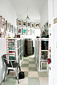 Display cabinets and gallery of pictures in hallway with chequered floor