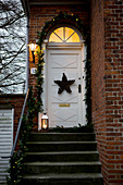 Weihnachtlich dekorierte Treppe und Haustür zum Backsteinhaus