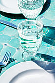 Glasses of water on plates on a tiled floor