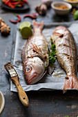 Rohe Fische mit Zutaten auf Ofenblech