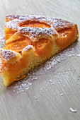 A slice of apricot cake dusted with icing sugar