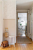 Stool against wall with dado in hallway with wooden floor