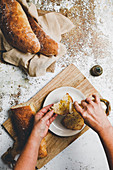 Knusprig gebackene Weissbrote, Olivenöl auf Brotscheibe träufeln
