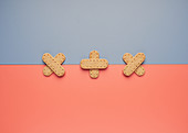 Delicious crispy cookies arranged in shape of crossed patch on line between gray and coral backgrounds