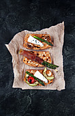 Homemade toasted bread served with green asparagus wrapped in bacon, cheese, avocado slices, grilled tomato cherry and nuts