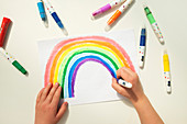 Boy colouring in a rainbow