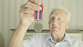 Senior man holding war medal