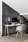 Scandinavian-style desk against grey wall below sloping ceiling