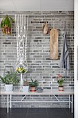 Fruit bowl in macrame hanger suspended from rod in front of brick wall