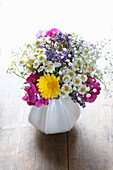 A mini bouquet of garden flowers in white, pink and yellow