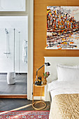 Abstract painting above bed and view into modern bathroom