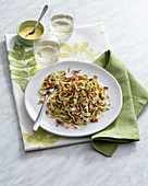 Spinach tagliatelle with a cheese sauce, ham and roasted nuts