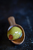 A green olive on a wooden spoon