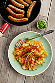 Sausages in a pan with a carrot and potato medley