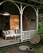 Rattan couch and arc lamp on wooden veranda