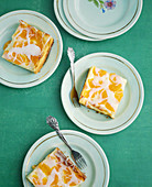 Slices of mandarin cake with sour cream on plates
