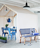 Garden bench and house-shaped tent over table and garden chairs in loft apartment
