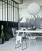 White metal table and wire chairs in black-and-white dining area of loft apartment