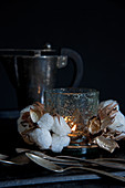 Cotton bolls around glass candle lantern against black background